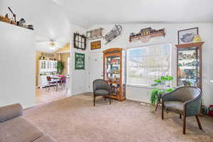 Sitting room featuring baseboards, a ceiling fan, carpet floors, visible vents, and lofted ceiling