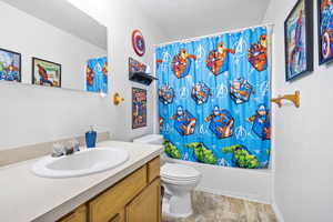 Bathroom featuring shower / tub combo, toilet, vanity, and a textured ceiling