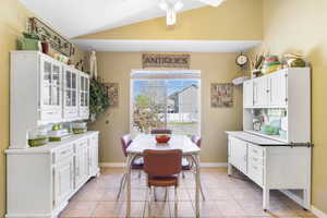 Dining area featuring light tile patterned floors, baseboards, a ceiling fan, and vaulted ceiling