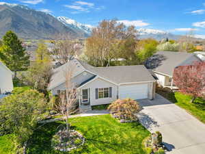 View of front of property with concrete driveway, a front yard, a mountain view, and an attached garage