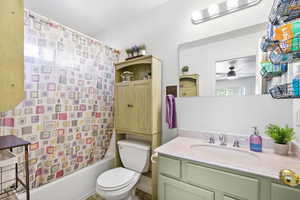 Full bathroom with shower / bath combo with shower curtain, vanity, a ceiling fan, and toilet