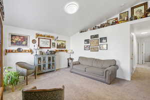 Carpeted living room with baseboards and lofted ceiling