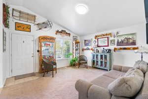 Carpeted living room with tile patterned floors, baseboards, and vaulted ceiling