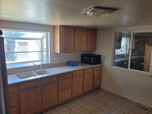 Kitchen with black microwave, light tile patterned floors, light countertops, visible vents, and a sink