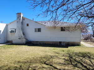 Back of property with a yard, cooling unit, and a chimney