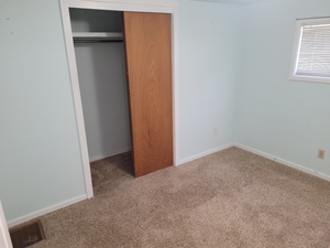 Unfurnished bedroom with visible vents, baseboards, carpet flooring, and a closet