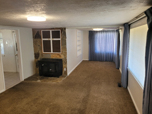 Unfurnished living room featuring carpet, a textured ceiling, and baseboards
