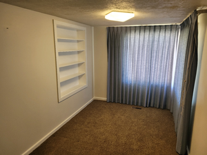 Carpeted empty room with built in features, baseboards, visible vents, and a textured ceiling
