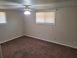 Carpeted empty room with baseboards and ceiling fan