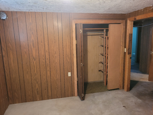 Hallway featuring wood walls and unfinished concrete flooring