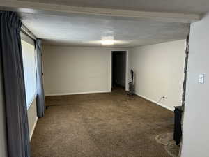 Unfurnished room with carpet floors, baseboards, and a textured ceiling