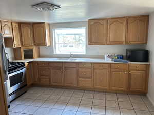 Kitchen with a sink, light countertops, appliances with stainless steel finishes, and light tile patterned flooring
