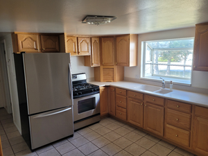 Kitchen with light tile patterned flooring, light countertops, a sink, and appliances with stainless steel finishes
