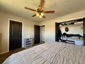 Bedroom with baseboards, carpet floors, a textured ceiling, a closet, and a ceiling fan