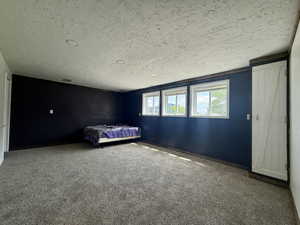 Unfurnished bedroom featuring a textured ceiling, carpet flooring, and baseboards