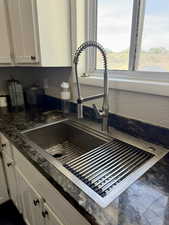 Kitchen view of a sink and white cabinetry