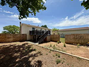 Back of property featuring stairs, a wooden deck, a fenced backyard, a gate, and a chimney