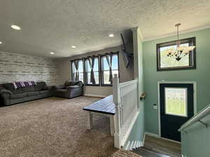 Living area featuring a chandelier, baseboards, a textured ceiling, recessed lighting, and carpet flooring