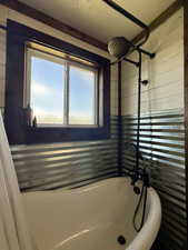 Full bath featuring wood walls and a textured ceiling