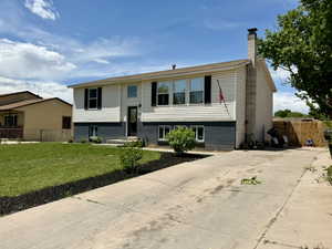 Raised ranch with a chimney, brick siding, and concrete driveway