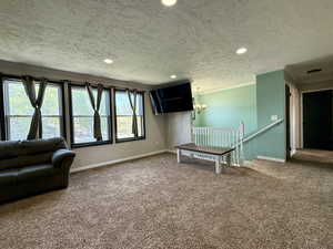Sitting room featuring carpet floors, ornamental molding, a textured ceiling, recessed lighting, and an upstairs landing
