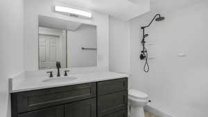 Bathroom featuring a shower, vanity, and toilet