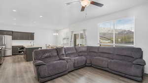 Living area featuring light wood-style flooring, ceiling fan with notable chandelier, and recessed lighting