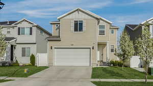 View of front of house featuring an attached garage, board and batten siding, fence, a front lawn, and driveway