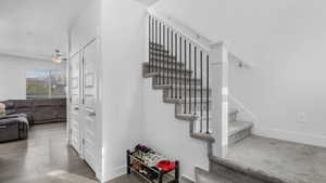 Stairs with wood finished floors, ceiling fan, and baseboards