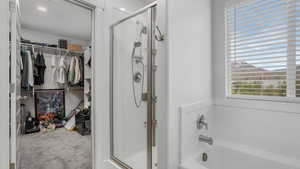 Full bathroom with a tub, a walk in closet, and a stall shower