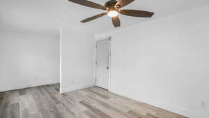 Empty room featuring light wood finished floors, ceiling fan, and baseboards