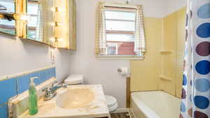 Bathroom with toilet, vanity, and shower / bath combination with curtain