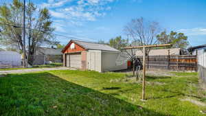 View of yard with an outbuilding, a detached garage, and fence