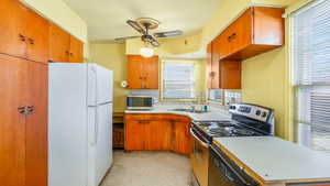 Kitchen featuring ceiling fan, light countertops, a sink, stainless steel appliances, and decorative backsplash