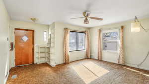 Carpeted foyer entrance with visible vents, baseboards, and a ceiling fan
