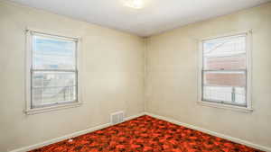 Unfurnished room featuring visible vents, a wealth of natural light, and baseboards