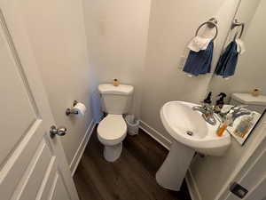 Bathroom with toilet, baseboards, a sink, and wood finished floors