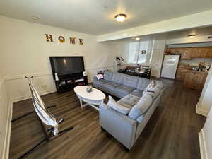 Living room featuring a textured ceiling and dark wood-type flooring