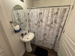 Bathroom with a shower with curtain and wood finished floors