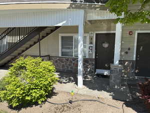 Doorway to property with covered porch and stone siding