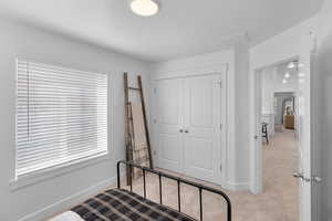 Carpeted bedroom featuring a closet and baseboards