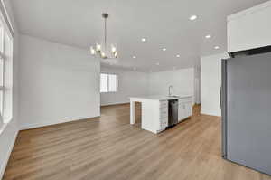 Kitchen with recessed lighting, open floor plan, white cabinetry, appliances with stainless steel finishes, and a sink