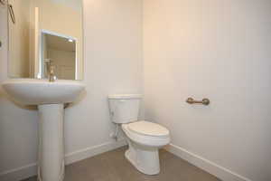 Half bathroom with toilet, baseboards, and tile patterned flooring