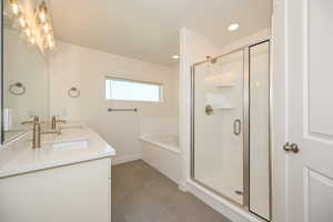 Primary bath featuring a sink, a shower stall, double vanity, and a garden tub