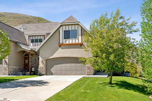 Tudor house featuring concrete driveway, stucco siding, stone siding, and a front lawn