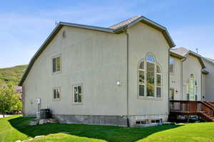View of property exterior featuring cooling unit, a yard, and stucco siding