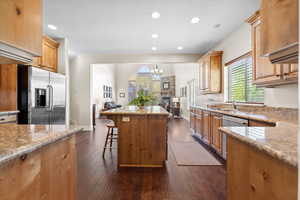 Kitchen featuring light stone countertops, a stone fireplace, a kitchen island, a breakfast bar, and stainless steel appliances
