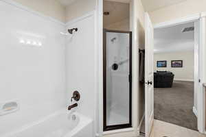 Full bath featuring combined bath / shower with glass door, tile patterned flooring, visible vents, and baseboards