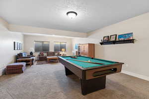 Recreation room featuring carpet floors, baseboards, pool table, and a textured ceiling