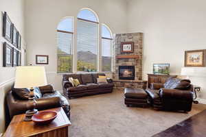 Living area featuring a high ceiling, a stone fireplace, and carpet